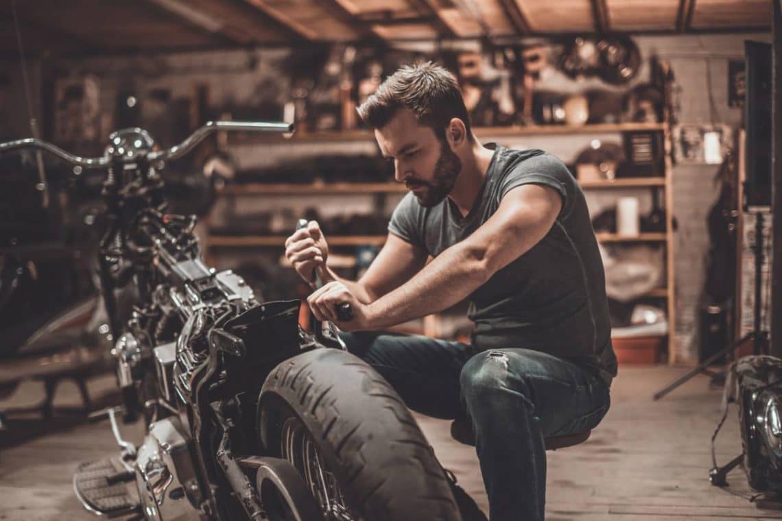 Une personne en train de réparer lui même sa moto dans le garage de sa maison