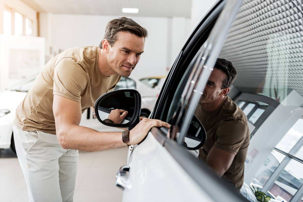 Une homme en train de choisir une voiture neuve à commande chez un concessionnaire auto